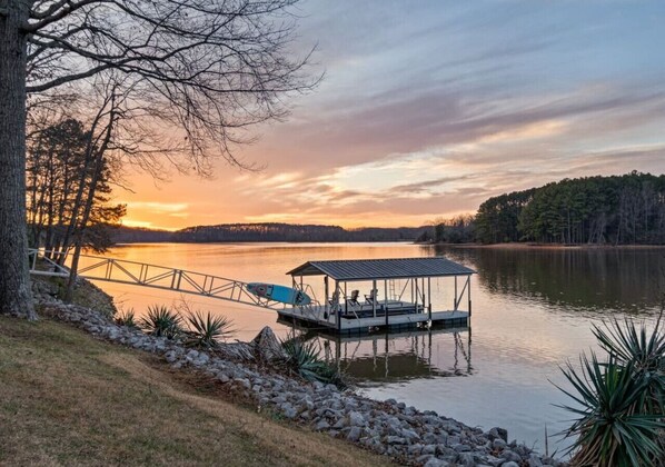 A dock with a covered seating area and a kayak, surrounded by calm water and trees. - Sunkissed Shores-Rare Flat Lot w/Beautiful Views, Dock, Hot Tub (Winchester)