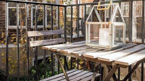 Eine Außenpatio mit Holztisch und Bänken, umgeben von einem Metallgeländer.