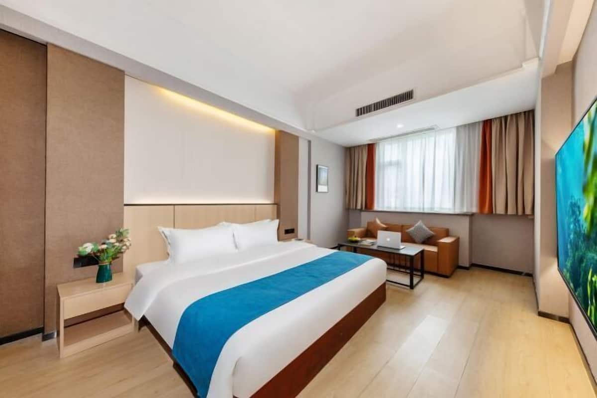 A hotel room with a large bed, a desk, a chair, and a TV.