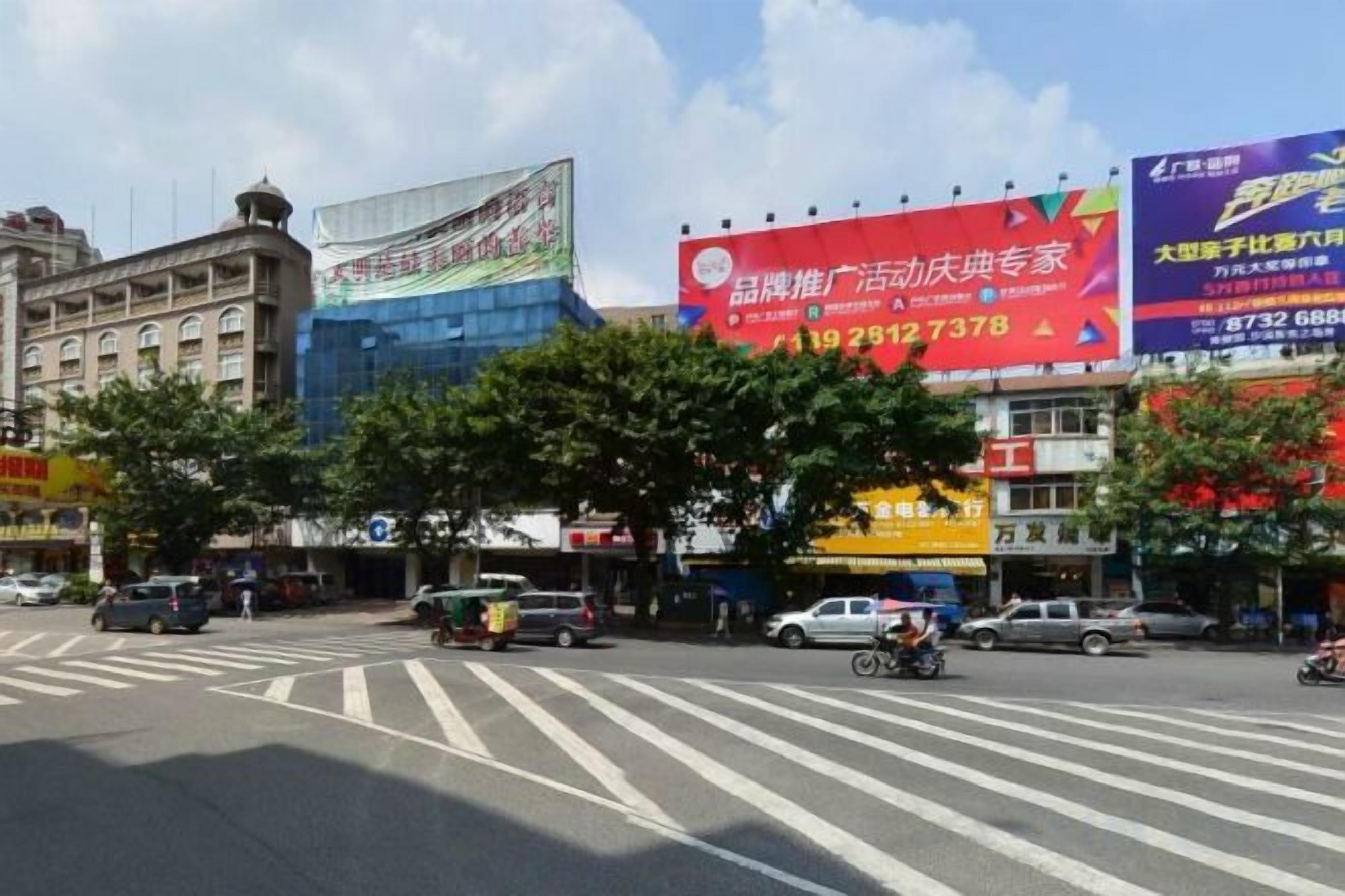 A street intersection with traffic lights, a pedestrian crossing, and commercial buildings with large billboards.