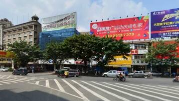 A street intersection with traffic lights, a pedestrian crossing, and commercial buildings with large billboards.