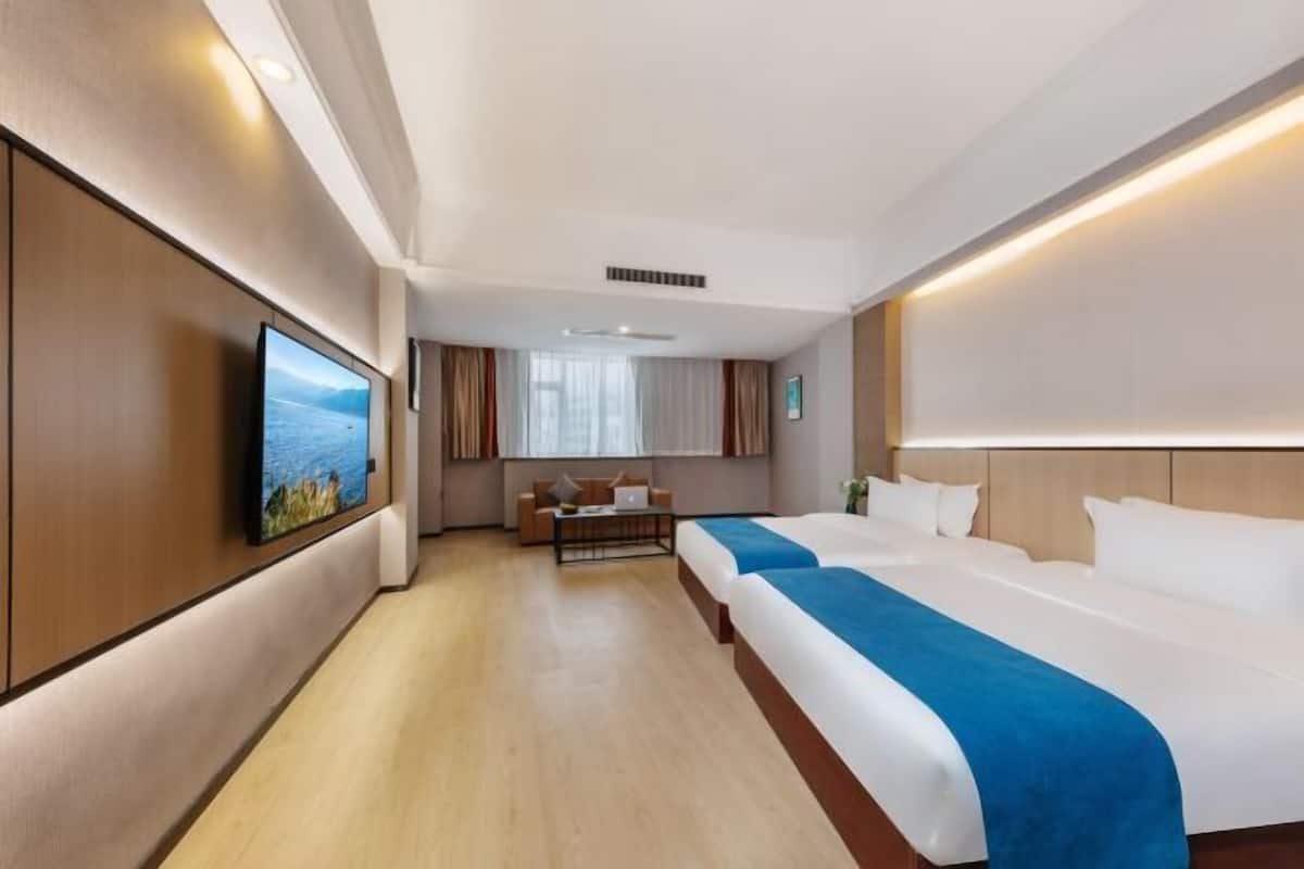 A hotel room with a large bed, a desk, a TV, and a view of the city.