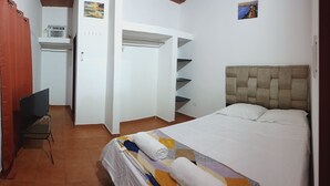 A bedroom with a bed, a wardrobe, a desk, and a chair.