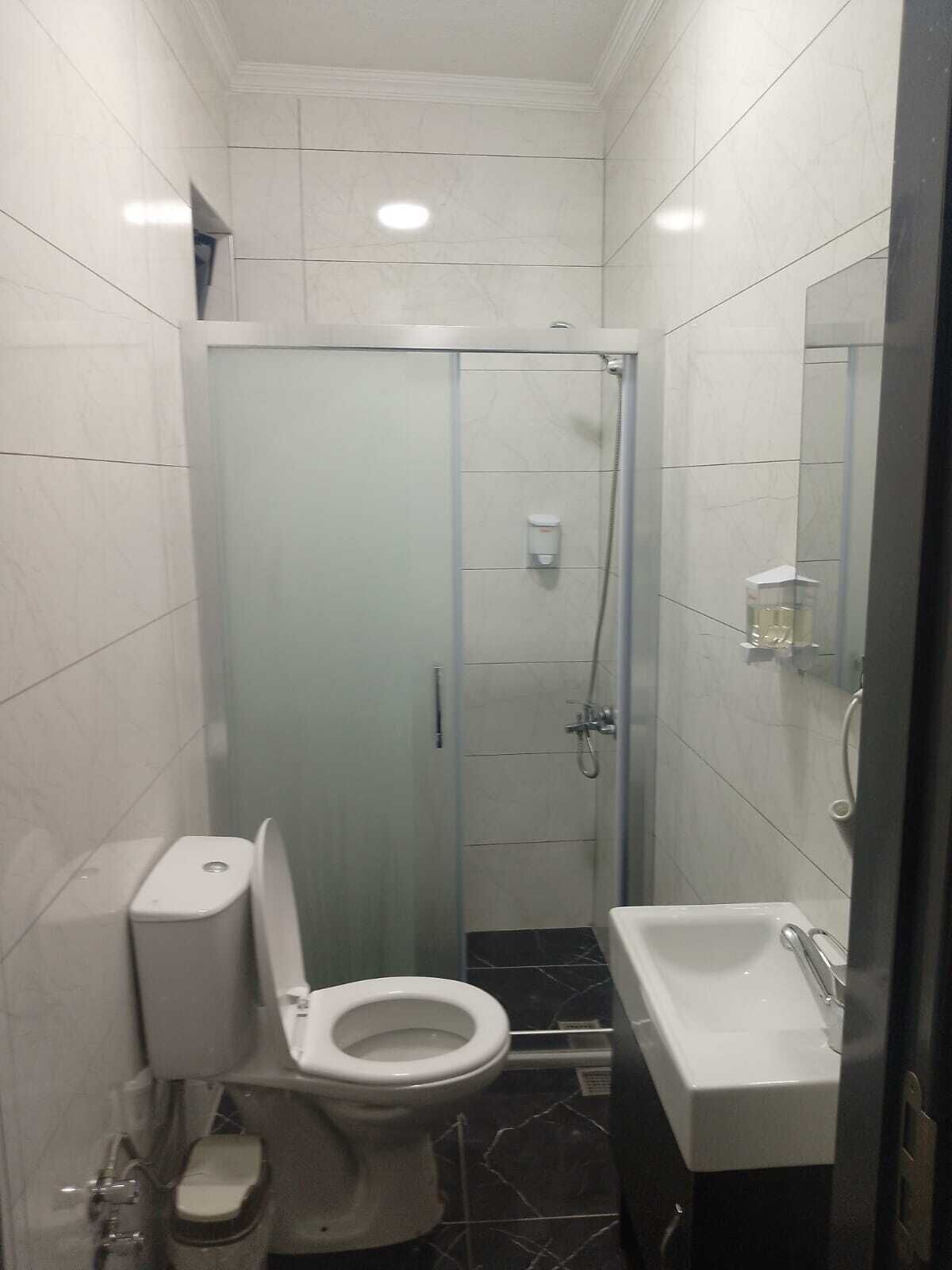 Un baño pequeño con inodoro, cabina de ducha y lavamanos.
