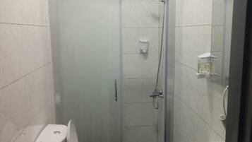Un baño pequeño con inodoro, cabina de ducha y lavamanos.