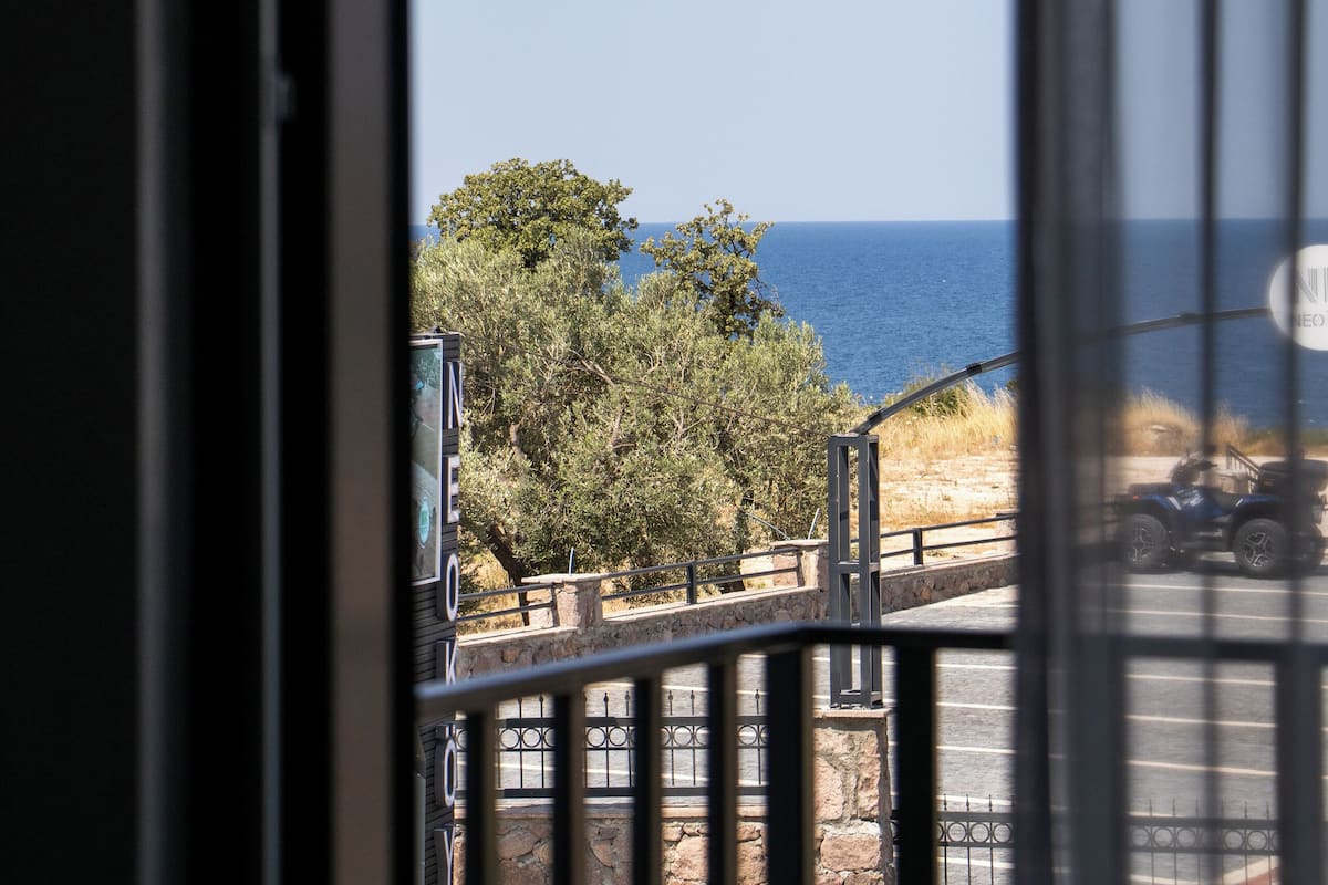 A view from a balcony with a stone wall, a metal railing, and a clear blue sky.