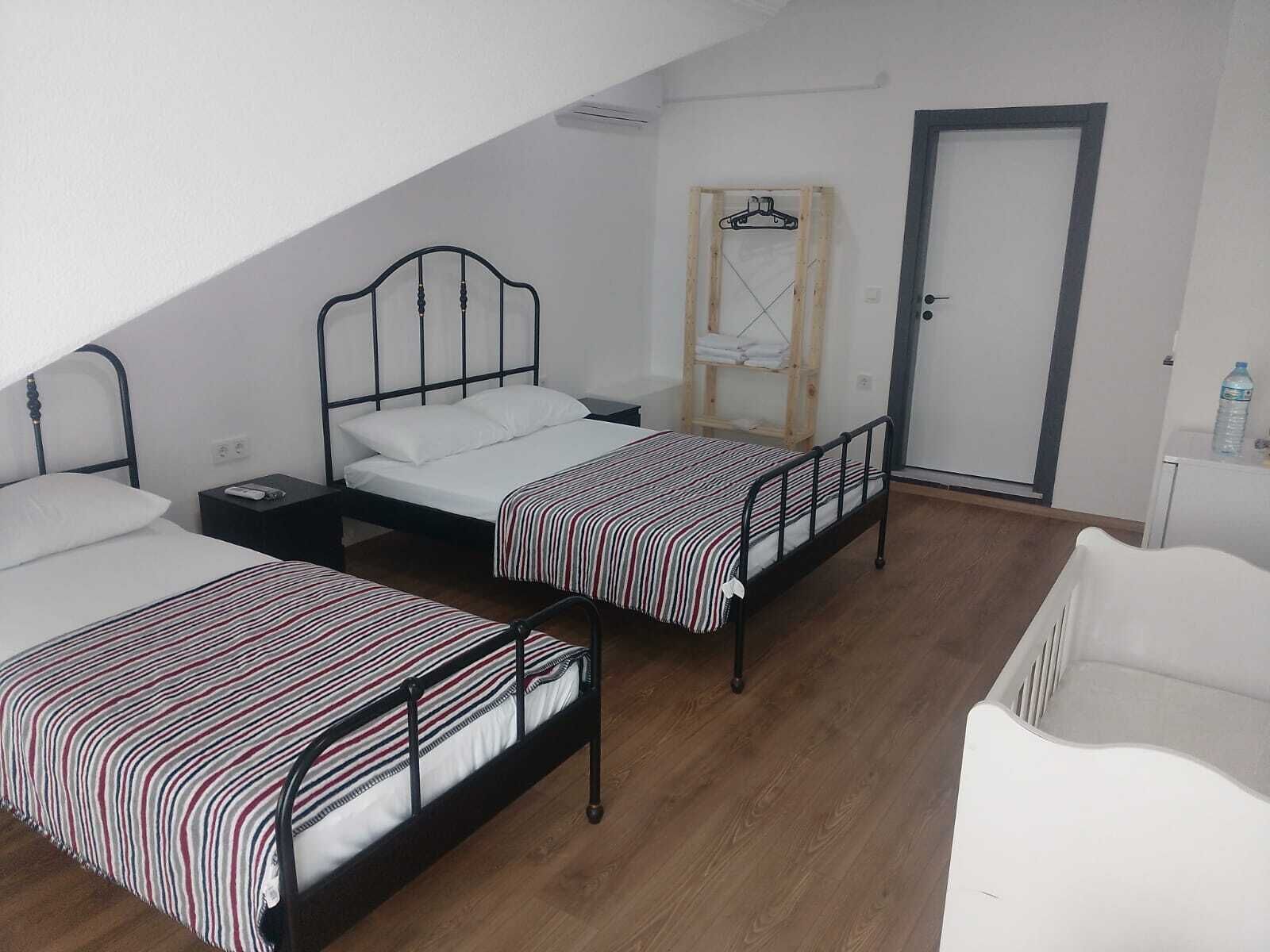 A room with two beds, a wooden wardrobe, a white door, and a white chair.