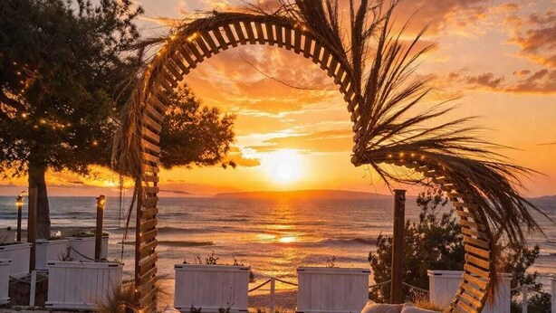 A beach setting with a wooden arch, lounge chairs, and lanterns. - Rose Otel (Ezine)