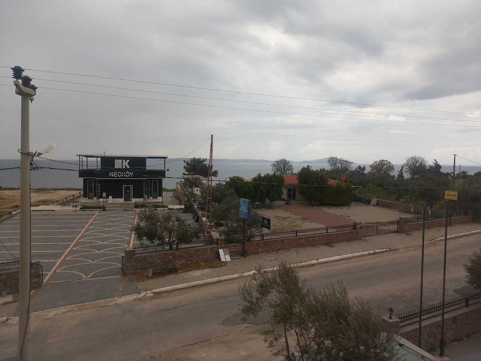 Um edifício com uma placa que diz 'NEKROY' e um estacionamento à frente.