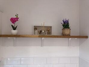 A kitchen shelf features a pot, a welcome sign, and a woven basket.
