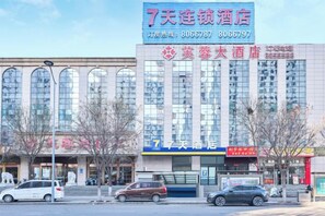 A hotel with a large sign, multiple windows, and a few parked cars in front. - 7Days Hotel (Shanxi Baqiuen Hospital West Gate) (Taiyuan)