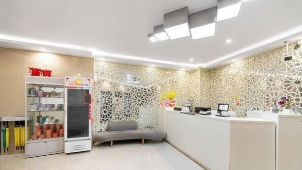 Un área de recepción con mostrador blanco, máquina expendedora y pared con diseño.
