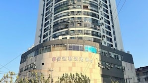 A tall, modern hotel building with multiple floors and balconies. - Sushi Select Hotel (Caoyang Road Subway Station) (Shanghai)