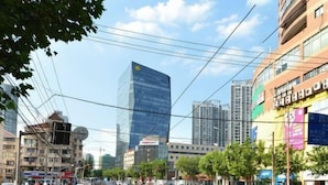 A city street with buildings, vehicles, and pedestrians. - Sushi Select Hotel (Caoyang Road Subway Station) (Shanghai)