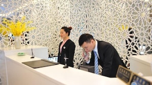 A reception desk with a modern, geometric patterned wall in the background. - Sushi Select Hotel (Caoyang Road Subway Station) (Shanghai)