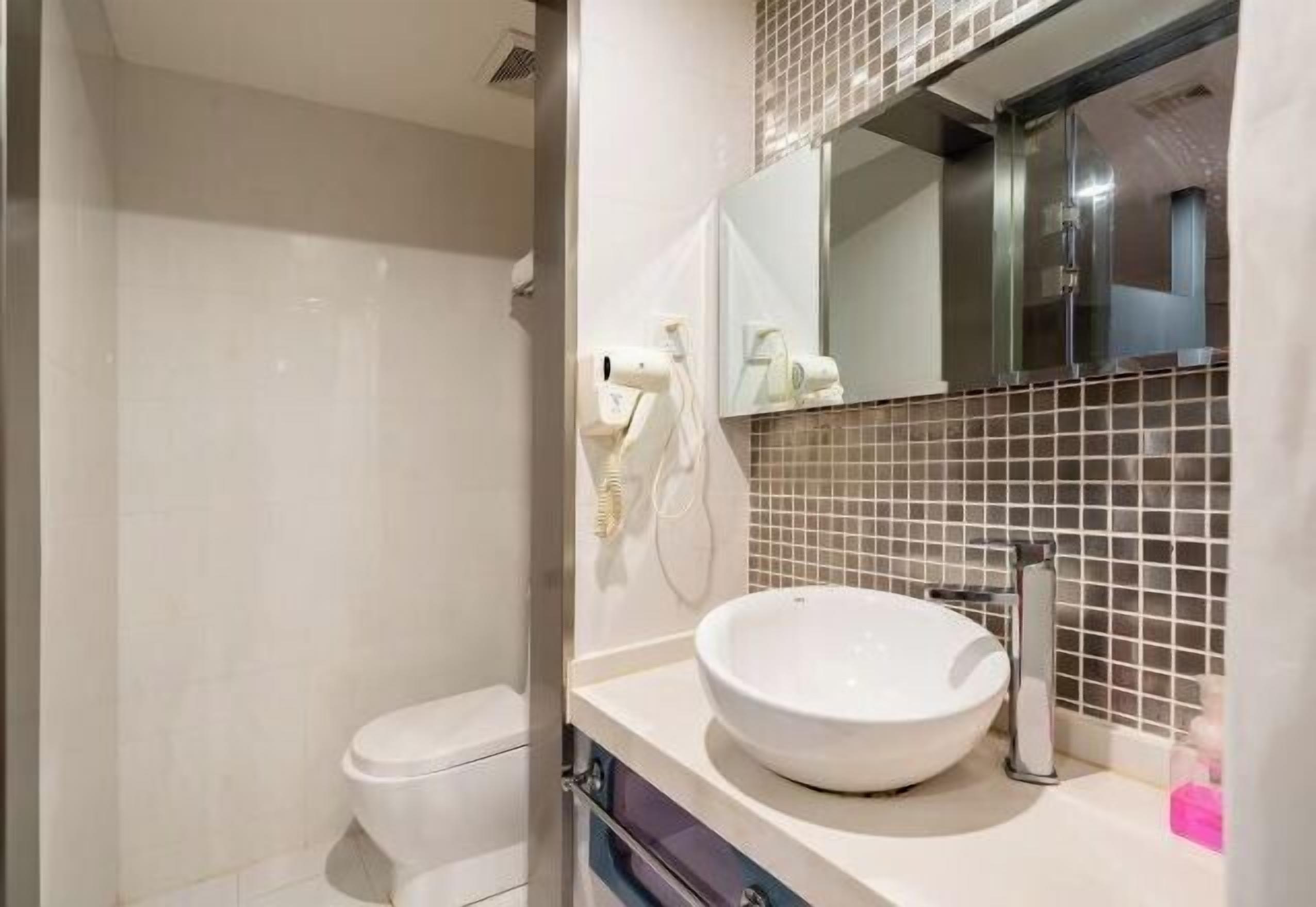 A bathroom with a white sink, a mirror, and a toilet.