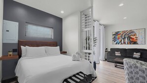 Una habitación de hotel moderna con una cama grande, un sofá y un cuadro en la pared.