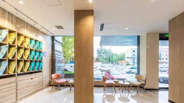 A modern hotel lobby with a wooden wall, colorful fabric display, and seating area with chairs and tables. - HanTing Premium Hotel (Linfen Gulou West Street Ancient City Wall) (Linfen)