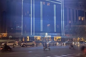 A hotel with a modern facade, illuminated vertical lines, and a sign indicating it is a hotel.