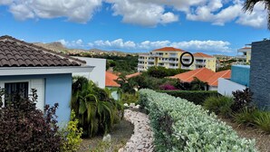 A residential area with a pathway leading to a building with a red-tiled roof. - Updated top-floor one-bedroom condo with amazing views in popular BlueBay Resort (Sint Michiel)