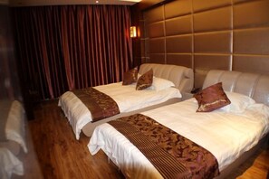 Camera d'albergo con due letti, pavimento in legno, una grande testiera imbottita e una tenda.