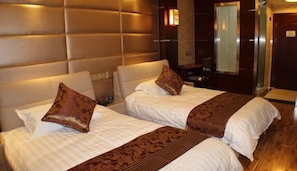 Een hotelkamer met twee bedden, een grote spiegel en een houten vloer.