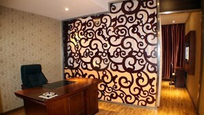 Una habitación con un escritorio de madera, una silla y un panel decorativo con un diseño de remolino.