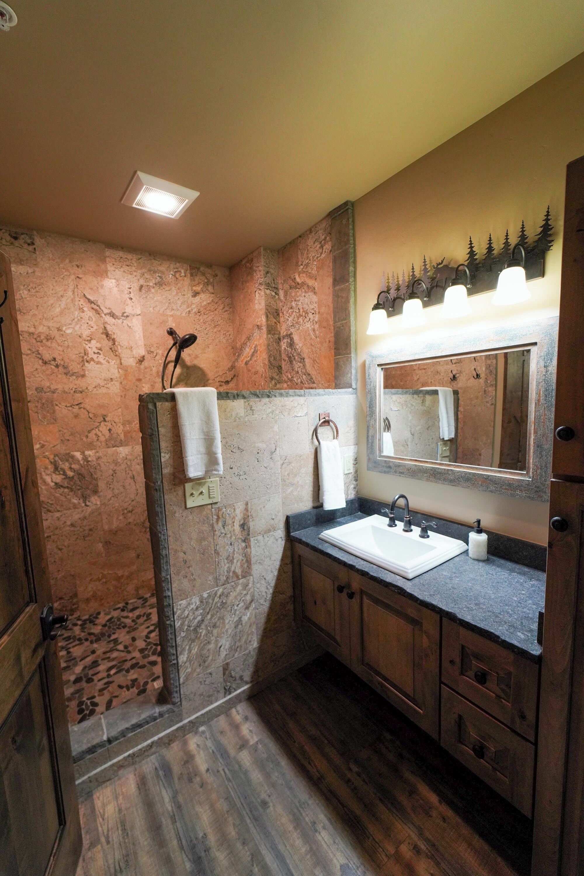 A bathroom with a stone wall, wooden cabinets, a sink, and a mirror.