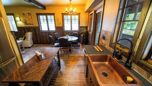 A kitchen with a wooden table, chairs, a sink, and a chandelier. - Apgar Lookout Suites (West Glacier)