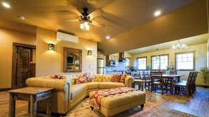 A spacious living room with a large sectional sofa, a wooden coffee table, and a dining area with a wooden table and chairs. - Apgar Lookout Suites (West Glacier)
