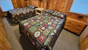Une chambre de style cabane avec deux lits, une petite table en bois et une commode.