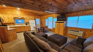 L’intérieur d’une cabine est aménagé avec du bois, il comprend un canapé, une table à manger et un coin cuisine.