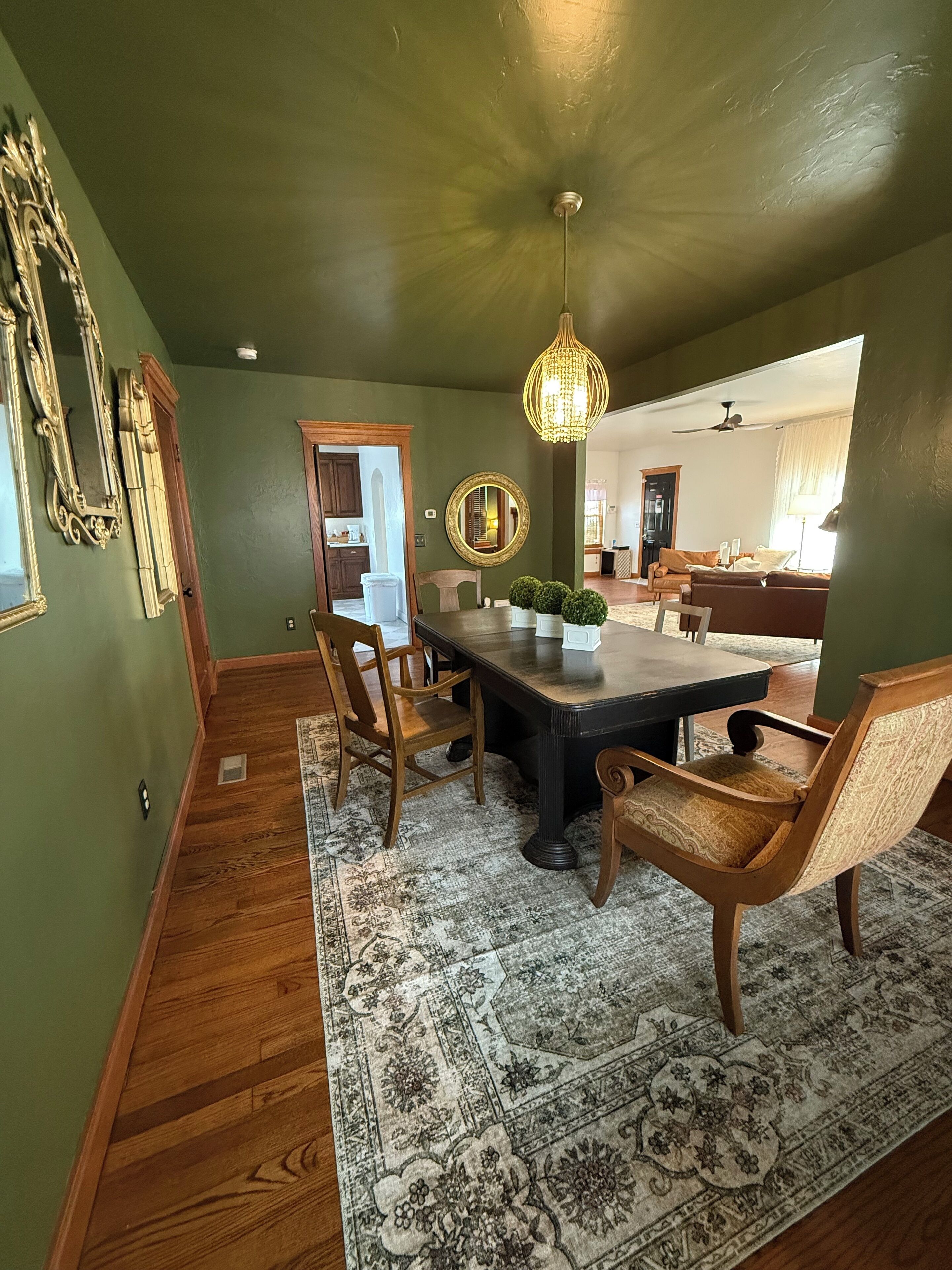 Un espace repas comprenant une grande table, des chaises, un lustre et un tapis à motifs.