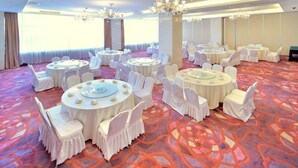 A banquet hall with round tables, white chairs, and a patterned carpet. - Elong Hotel (Shenyang)
