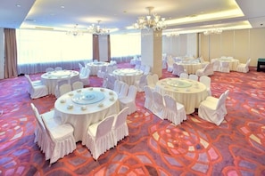 A banquet hall with round tables, white chairs, and a patterned carpet. - Elong Hotel (Shenyang)