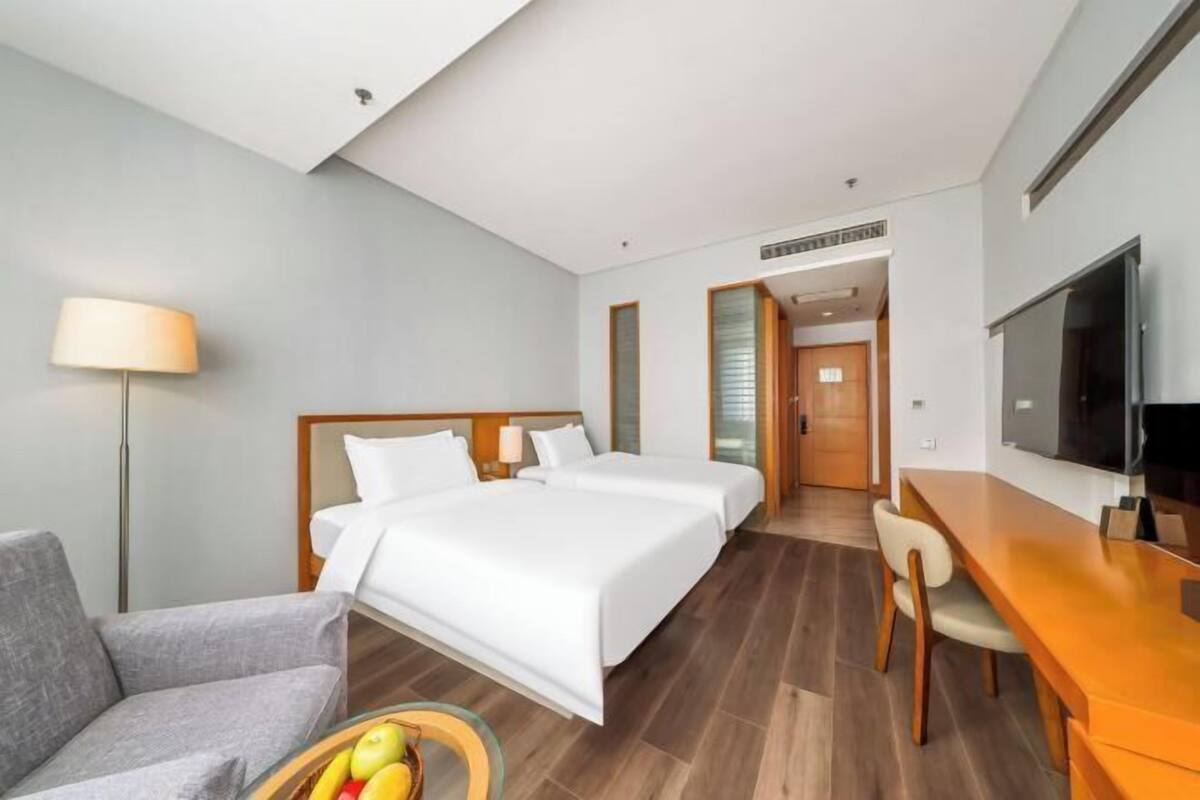 Une chambre d’hôtel avec un lit, un bureau, une chaise, une télévision et une lampe.