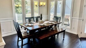 A dining room with a large wooden table set for four, surrounded by dark wooden chairs. - Lakefront Retreat with Pool and Room For Everyone! (Milledgeville)