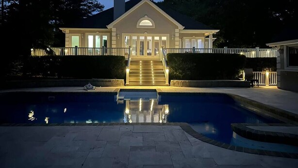 A large house with a swimming pool in front, a well-lit entrance, and a staircase leading to the front door. - Lakefront Retreat with Pool and Room For Everyone! (Milledgeville)