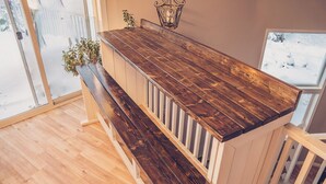 A wooden bench with a slatted backrest and a dark wooden table with a metal lantern on top. - Spacious, newly renovated home in the forest; close to world famous fishing. (Soldotna)