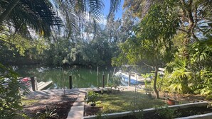 A serene garden with a pond, dock, and boats. - Waterfront Condo with Fishing, Paddleboard, and yard access. (North Miami)