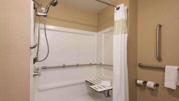 Une salle de bain équipée d’une douche, de barres d’appui, d’un porte-serviettes et de toilettes.