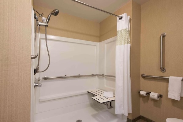 Baño con ducha, barras de apoyo, toallero y retrete.