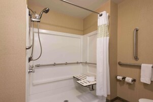 A bathroom with a shower, grab bars, a towel rack, and a toilet.