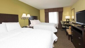 A hotel room with two beds, a desk with a television, a chair, and a desk lamp. - Hampton Inn & Suites LLC (Danville)