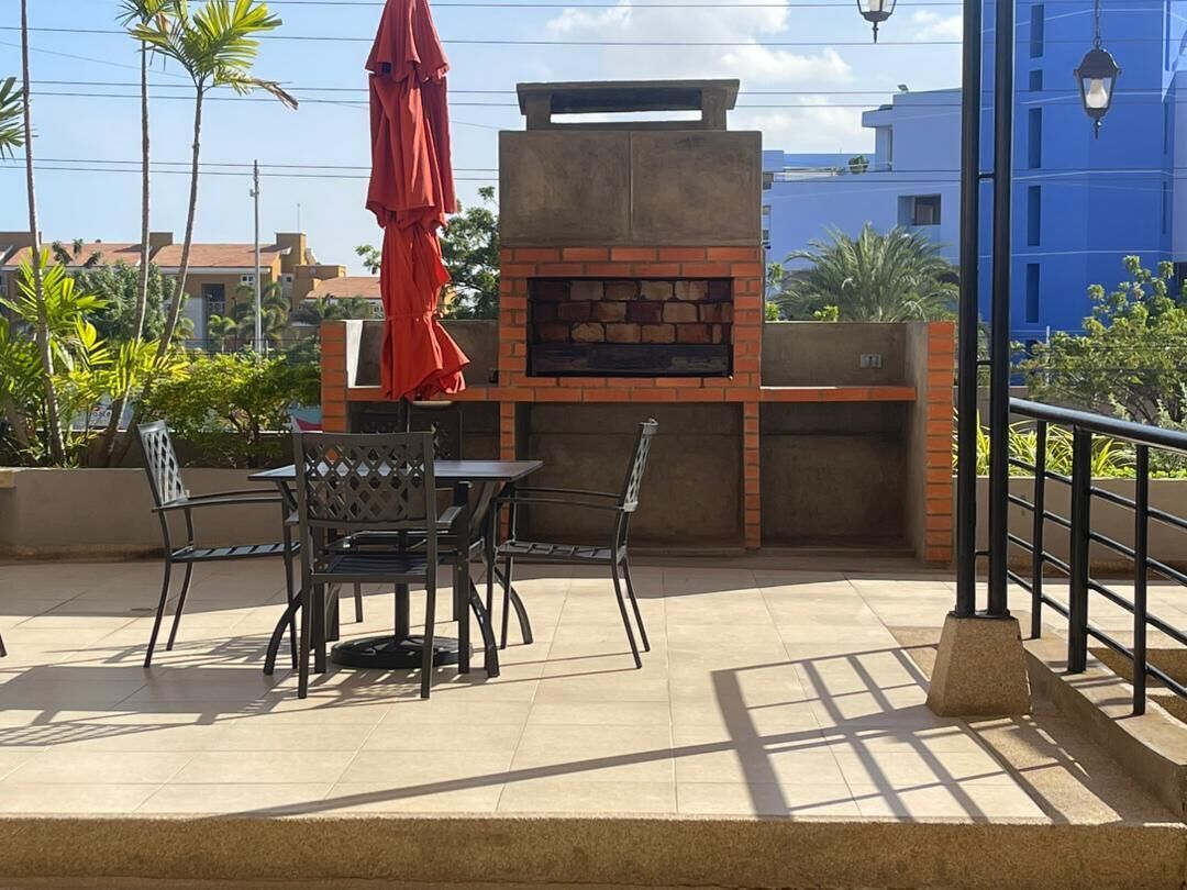 Une terrasse extérieure avec un four en briques, une table et des chaises.