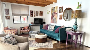 A living room with a teal sofa, a wooden coffee table, and a purple side table. - Curious cottage with Mountain View’s in downtown Black Mountain (Asheville)