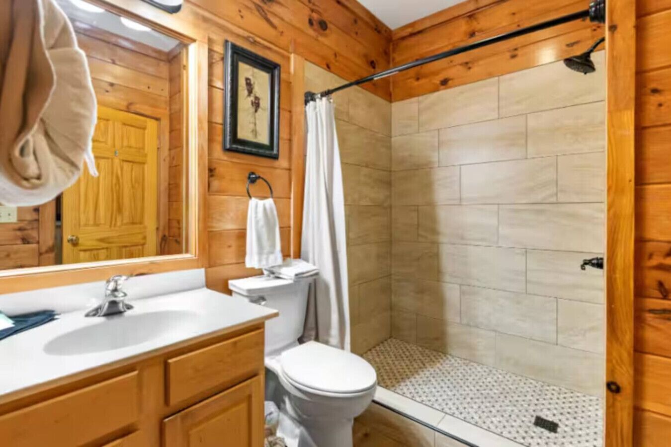 A wooden cabin bathroom with a shower, toilet, and sink.