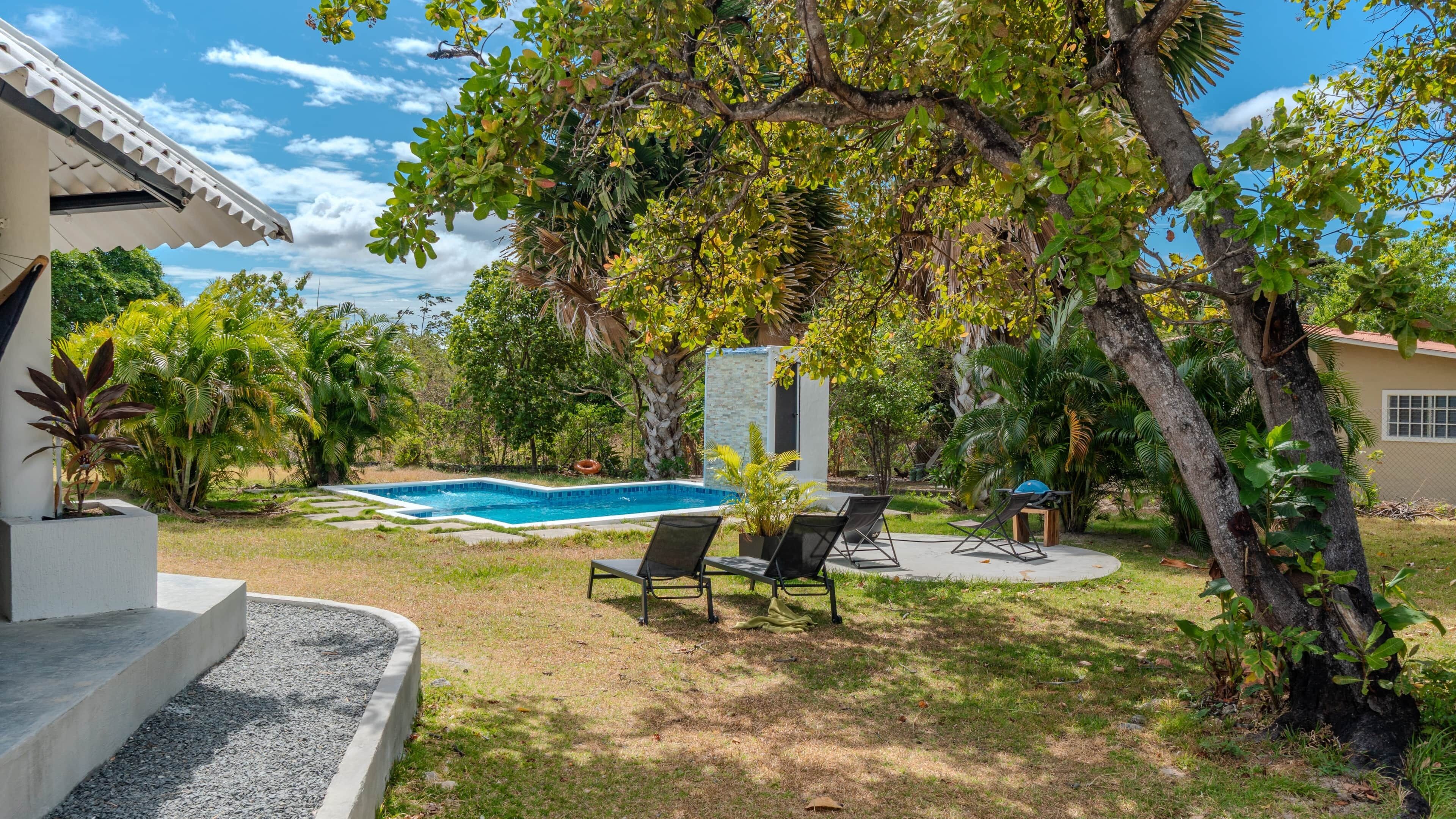 Ein Garten mit Swimmingpool, Sitzgelegenheiten im Freien und üppiger Bepflanzung.