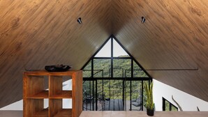 A modern interior with a wooden ceiling, a large window, and a wooden table with a bowl.