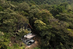 Une maison moderne, dotée d’un toit en pente, entourée d’une forêt dense.